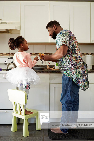 Mature man teaching daughter about kitchen knives in kitchen