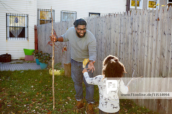 Girl handing autumn leaf to her father in garden