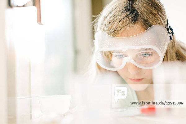 Mädchen macht wissenschaftliches Experiment  schaut durch eine Schutzbrille