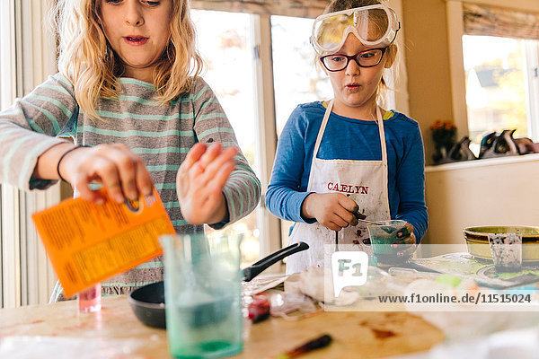 Zwei Mädchen machen ein wissenschaftliches Experiment und schütten ein Paket in die Bratpfanne