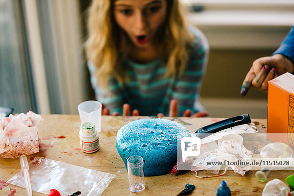 Mädchen beim wissenschaftlichen Experiment  überrascht von blauer Flüssigkeit  die in der Bratpfanne schäumt