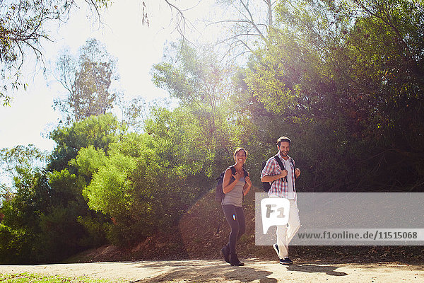 Mid adult couple hiking  walking along sunlit rural road