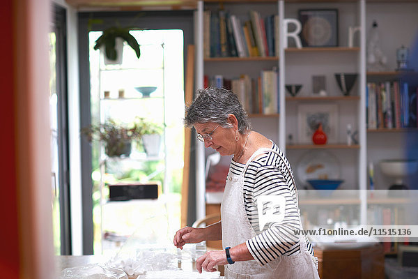 Ältere Frau in der Küche  die klare Töpfe auf der Arbeitsfläche anordnet