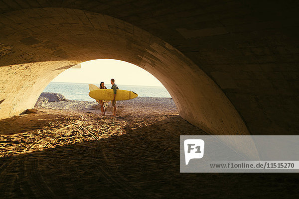 Surfing couple in underpass at Newport Beach  California  USA