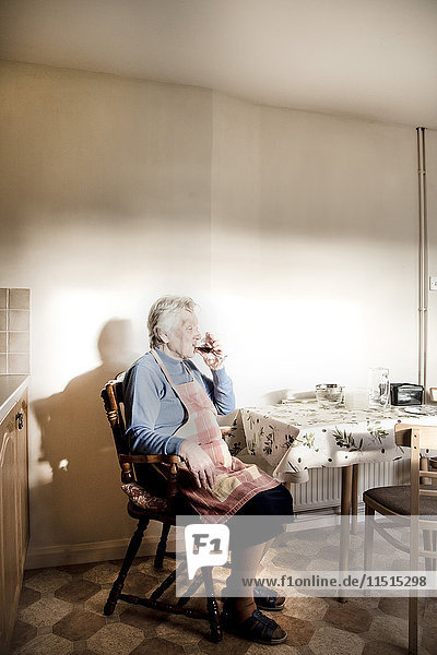 Woman sitting at dining table drinking sherry