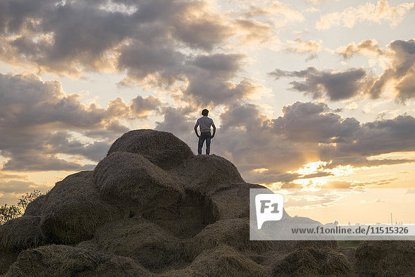 Kaukasischer Mann steht bei Sonnenuntergang auf einem Steinhaufen