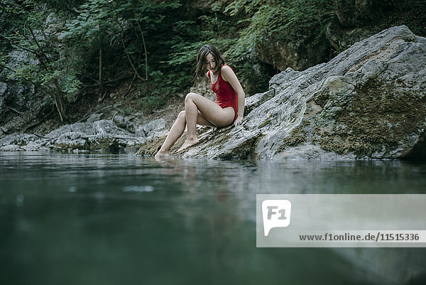 Kaukasische Frau sitzt auf Steinen an einem Wasserbecken