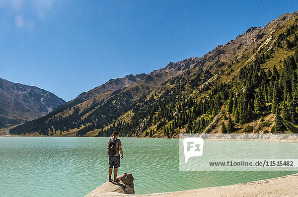 Caucasian man standing on rock near mountain lake