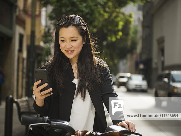 Chinese businesswoman on bicycle texting on cell phone