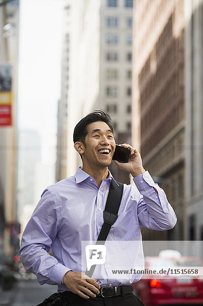 Chinese businessman talking on cell phone in city