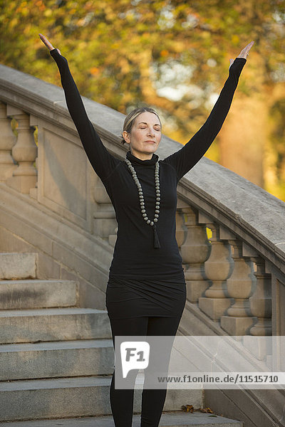 Caucasian woman meditating on staircase in park