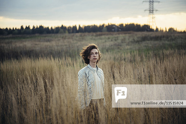 Kaukasische Frau steht in einem Feld mit hohem Gras