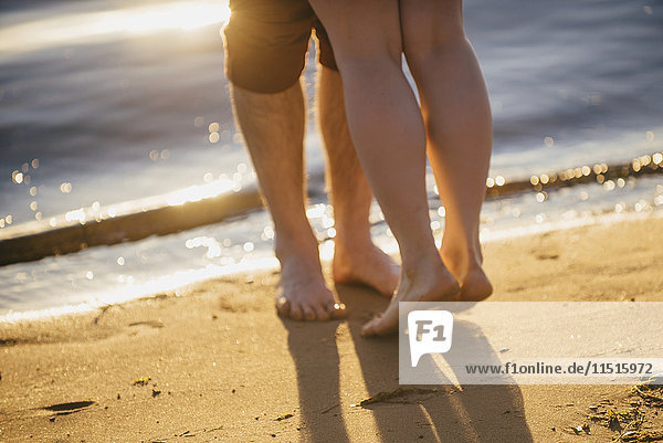 Beine eines Paares  das sich am Strand umarmt