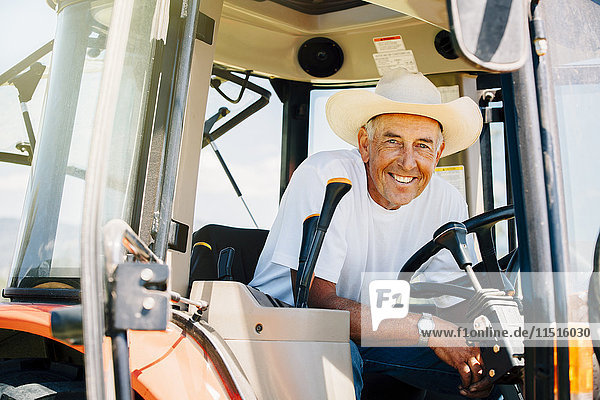 Porträt eines lächelnden kaukasischen Landwirts mit Traktor