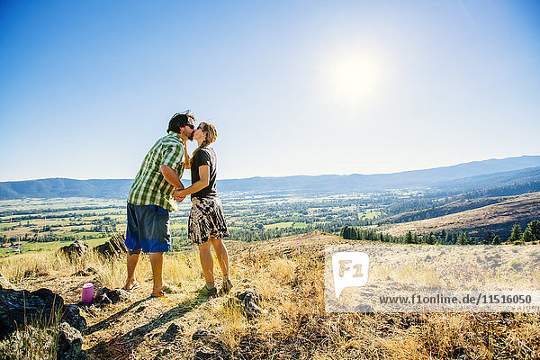 Caucasian couple standing on hill and kissing