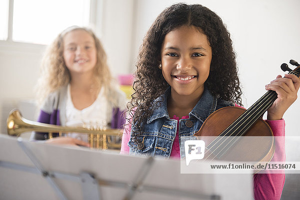 Smiling girls posing with violin and trumpet