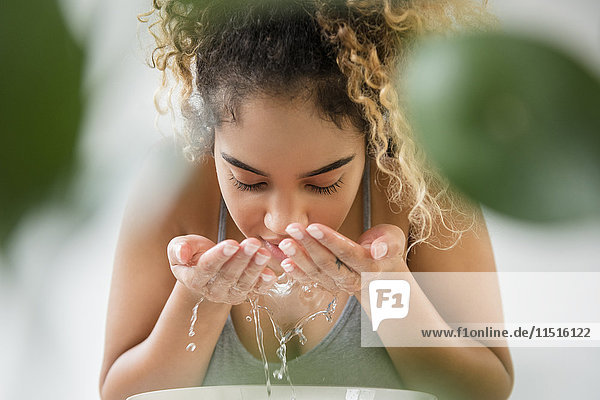 Mixed Race Frau spritzt Wasser auf Gesicht