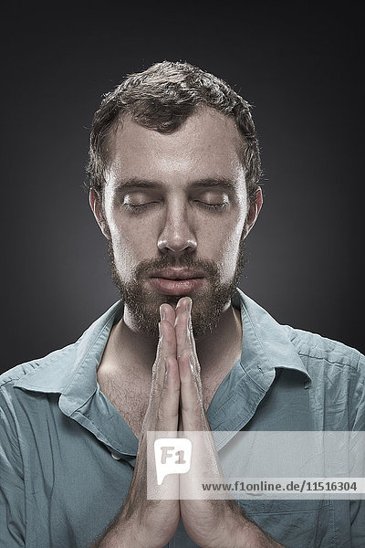 Serious man praying with eyes closed