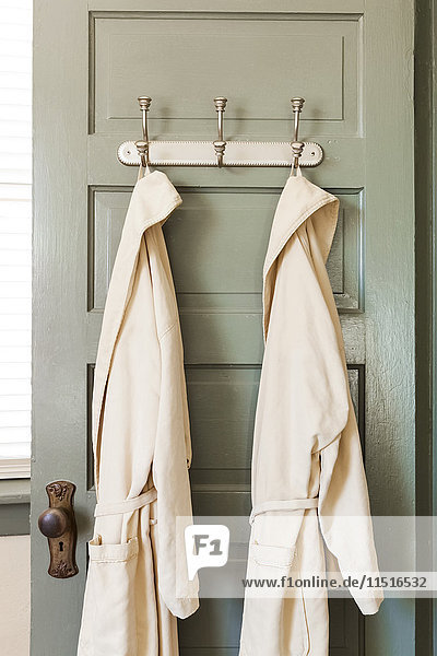 Bathrobes hanging on hooks on door