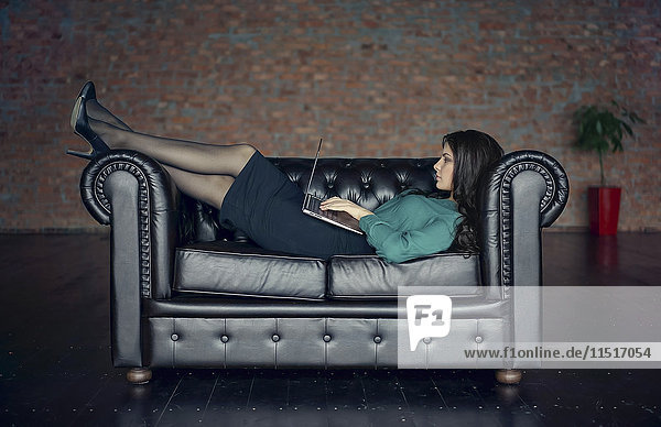 Kaukasische Geschäftsfrau auf dem Sofa liegend mit digitalem Tablet