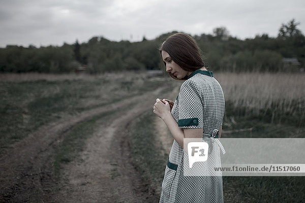 Pensive Caucasian woman standing near dirt road