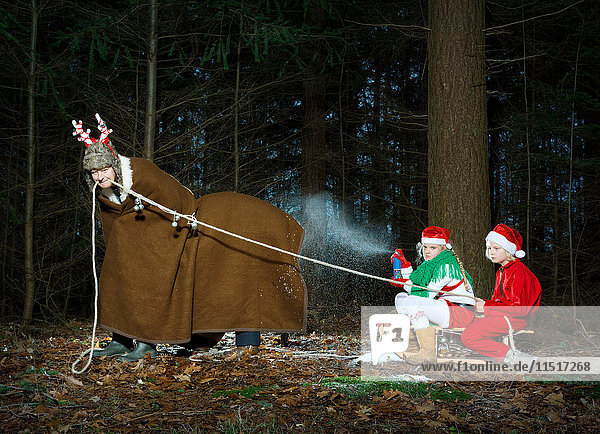 Father disguised as reindeer pulling sleigh with children in Santa costume