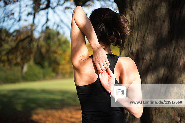 Frau macht am Herbsttag Yoga im Park