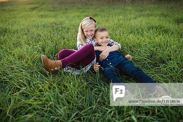 Bruder und Schwester legen sich gemeinsam ins Gras