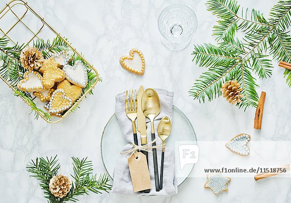 Weihnachtlich gedeckter Tisch mit Goldbesteck und Plätzchen