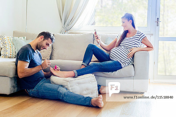 Man pampering pregnant woman on sofa