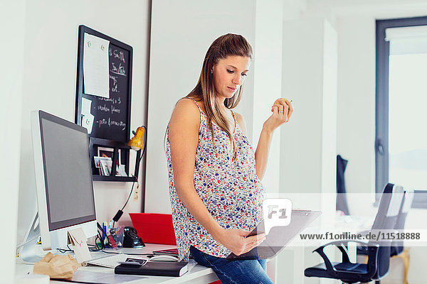 Schwangere Frau im Amt hält Klemmbrett