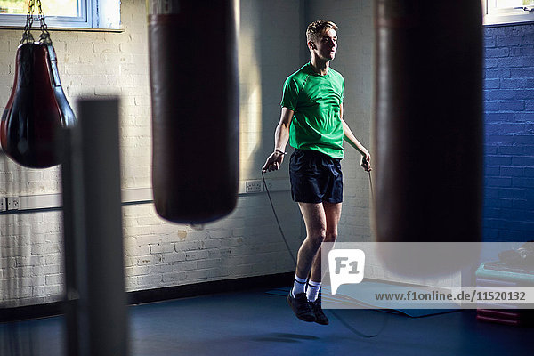 Junger männlicher Boxer springt im Fitnessstudio