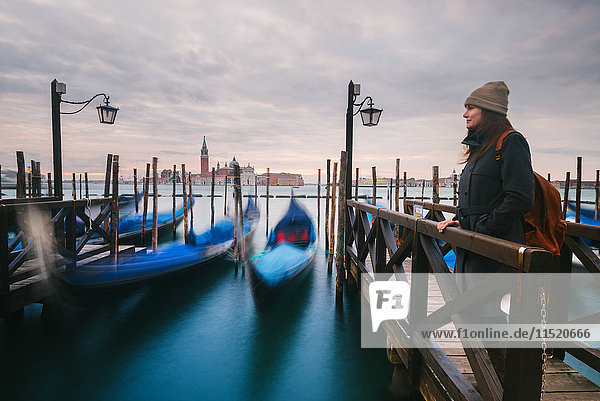 Woman on pier by gondolas in Grand Canal  San Giorgio Maggiore Island in background  Venice  Italy
