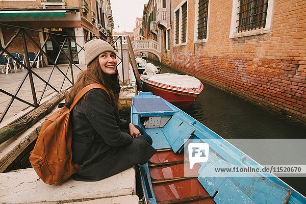 Woman sitting by canal  Venice  Italy