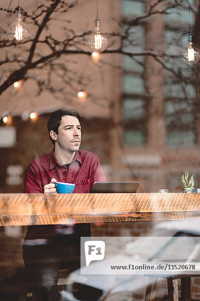 Mann schaut durch das Fenster eines Cafés