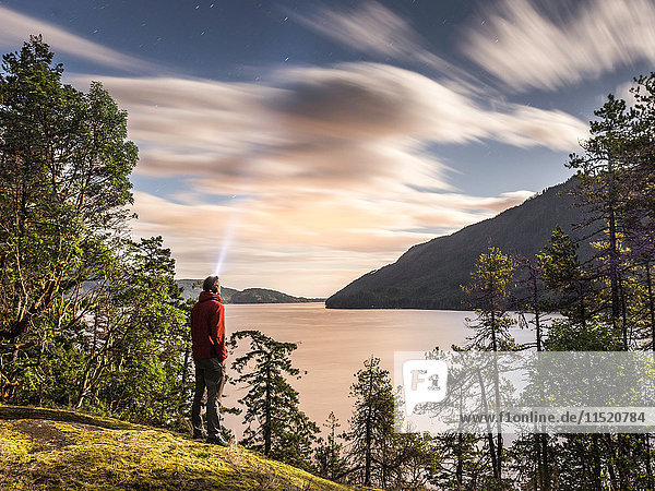 Male hiker looking up at evening stars Comox Lake Courtenay Vancouver Island British Columbia Canada