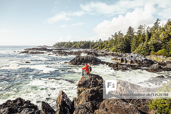 Male hiker looking out to sea from rocky coast Wild Pacific Trail Vancouver Island British Columbia Canada
