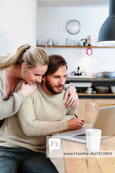 Mid adult couple looking at laptop in kitchen
