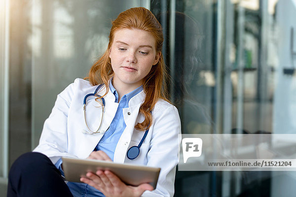 Junge Ärztin benutzt digitalen Tablet-Touchscreen am Eingang des Krankenhauses