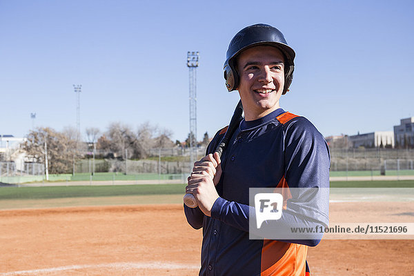 Lächelnder Baseballspieler mit einem Baseballschläger