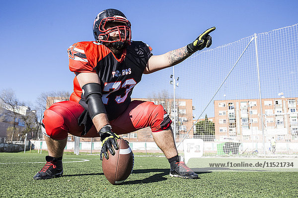 American football player with helmet and ball on sports field