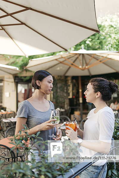 Zwei junge Frauen  die sich im Straßencafé unterhalten.