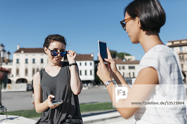 Italien  Padua  junge Frau beim Fotografieren ihrer Freundin mit dem Smartphone