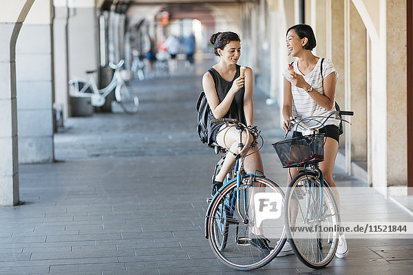 Zwei junge Frauen mit Fahrrädern beim Eis essen