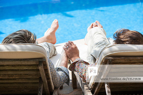 Rückansicht eines romantischen Männerpaares  das sich am Pool an den Händen hält  Mallorca  Spanien