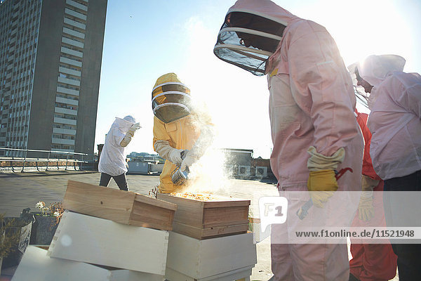 Imkerinnen und Imker mit Bienenraucher auf dem Stadtdach