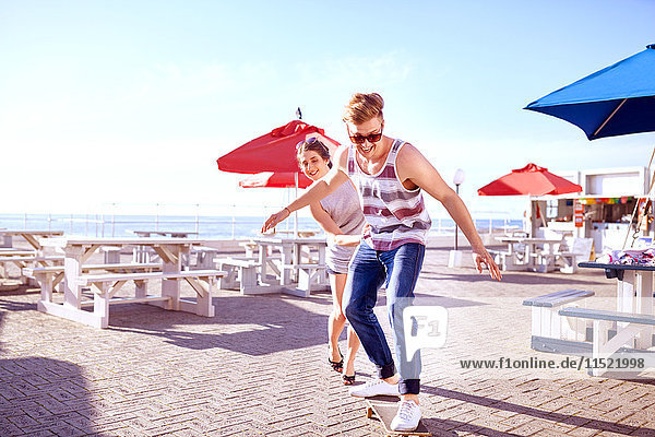 Paar mit Skateboard auf der Promenade