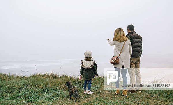 Familie mit Hund an der Küste an einem nebligen Wintertag mit Blick auf die Landschaft