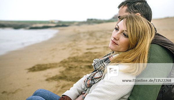 Couple in love sitting on the beach in winter