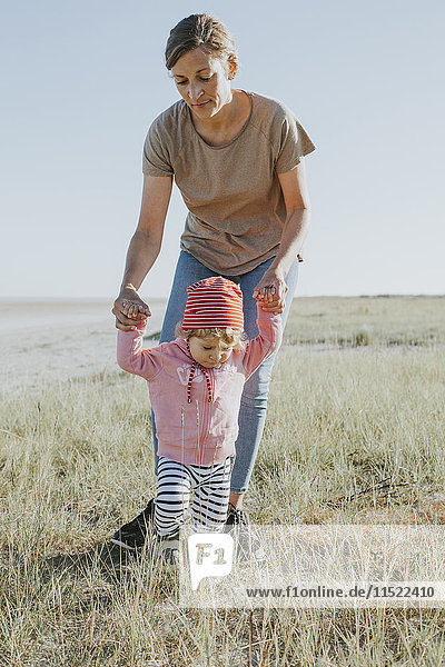 Niederlande  Schiermonnikoog  Mutter geht mit kleiner Tochter auf einer Wiese spazieren